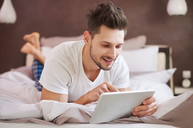 Man met behulp van een digitale tablet in de slaapkamer