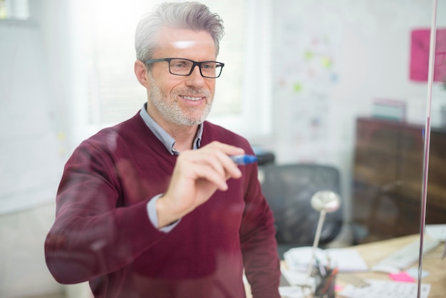 Man met behulp van glazen wand om wat informatie te schrijven