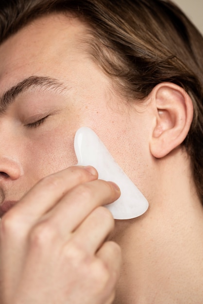 Man met behulp van gua sha tool close-up