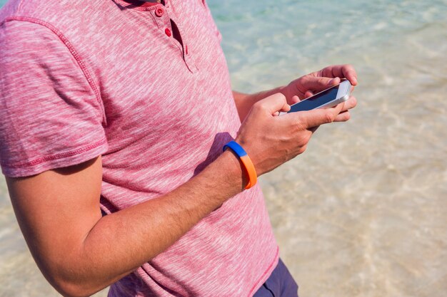 Man met behulp van mobiele telefoon op het strand