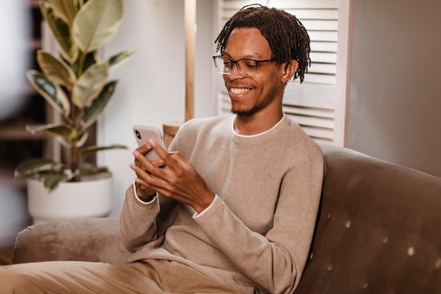 Man met behulp van moderne smartphoneapparaat terwijl hij op de bank thuis