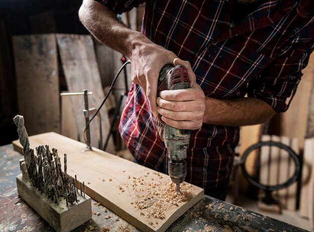 Man met boor die met hout werkt