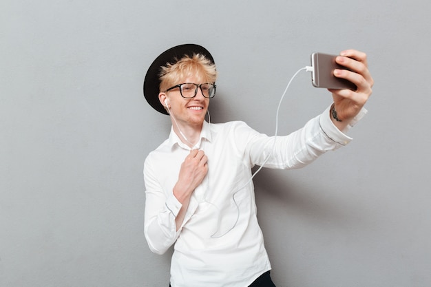 Man met bril luisteren muziek terwijl selfie maken.