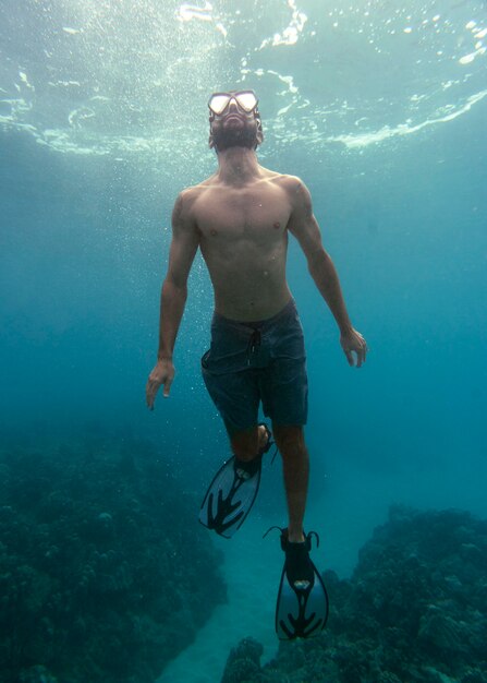 Man met duikuitrusting die in de oceaan zwemt