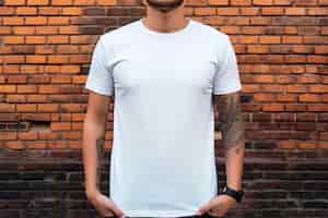 Gratis foto man met een blanco t-shirt, bakstenen muur achtergrond