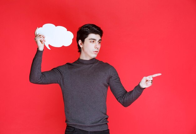 Man met een denkbord in de vorm van een wolk dat ergens naar wijst