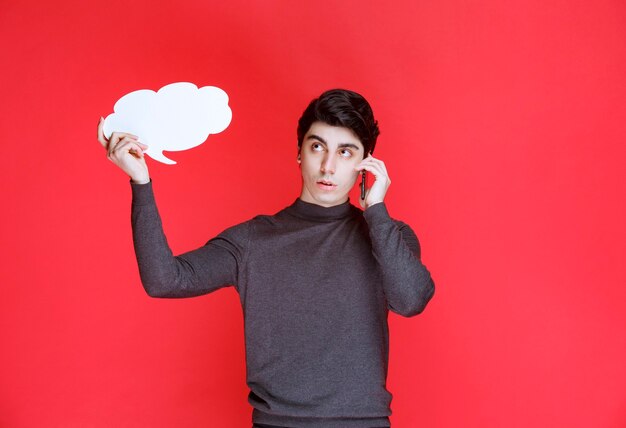 Man met een denkbord in de vorm van een wolk in gesprek met de telefoon