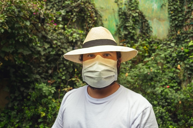 Man met een hoed met een wit gezichtsmasker ter bescherming tegen stof en coronavirus in de tuin