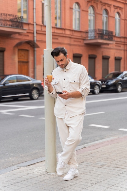 Man met een ijskoffiepauze tijdens het gebruik van smartphone buitenshuis