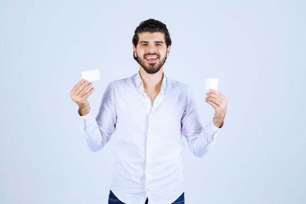 Man met een koffiekopje in de ene hand en zijn visitekaartje in de andere hand