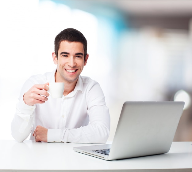 Man met een kopje koffie en een laptop