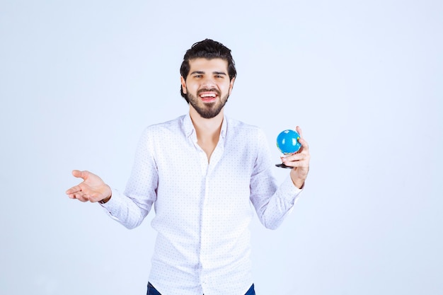 Man met een mini-wereldbol en kijkt verward