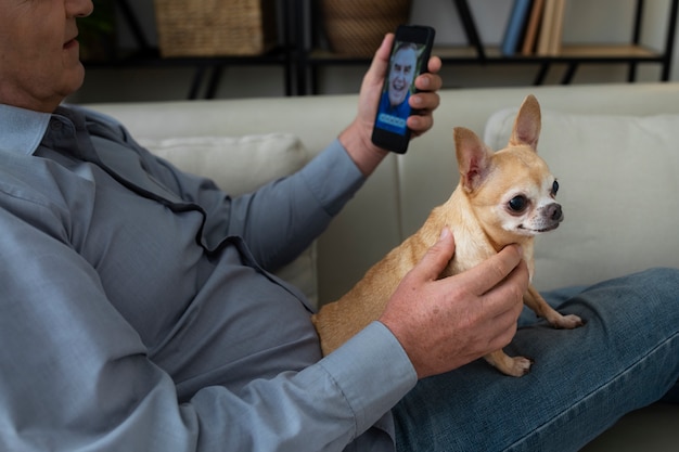 Gratis foto man met een smartphone thuis naast zijn hond