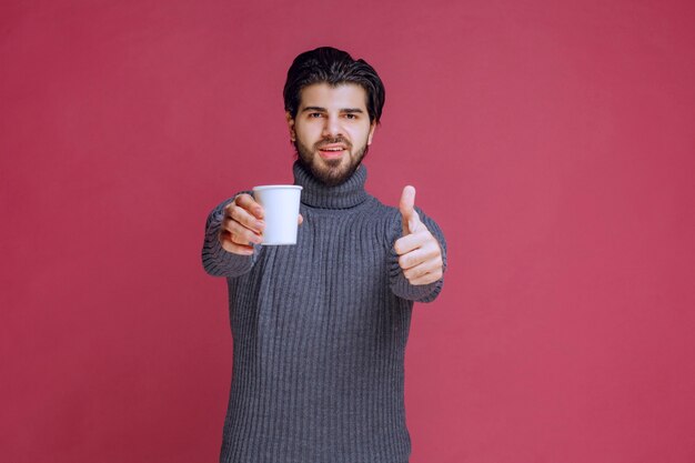 Man met een wegwerp koffiekopje en plezier teken maakt.