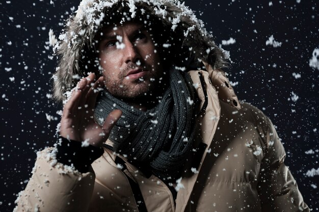 man met een winterjas terwijl het sneeuwt