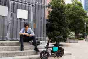 Gratis foto man met elektrische fiets in de stad met smartphone