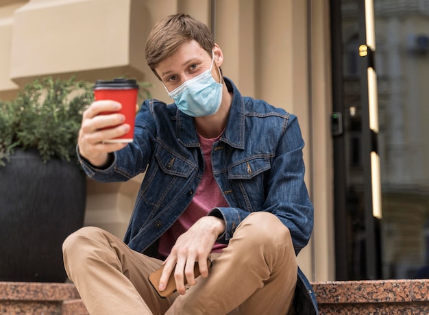 Man met gezichtsmasker juichen met een kopje koffie