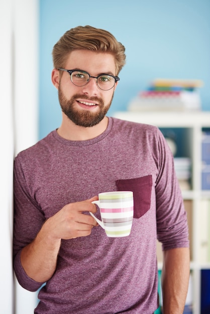 Man met koffie naast de muur