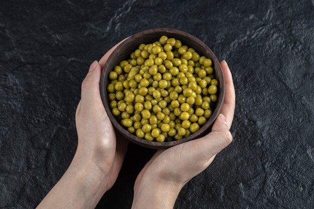 Man met kom gemarineerde groene erwten op zwarte tafel.