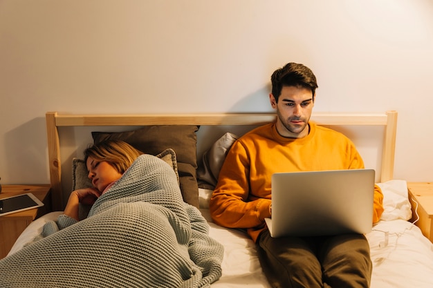 Man met laptop in de buurt van slapende vrouw