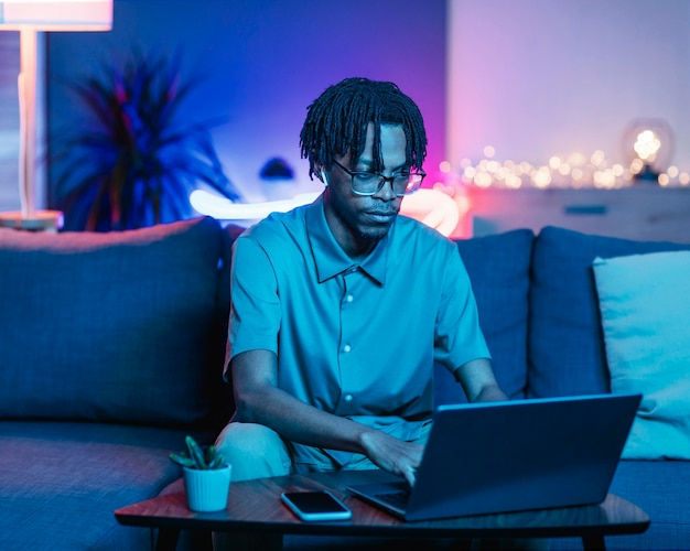 Man met laptop terwijl hij thuis op de bank