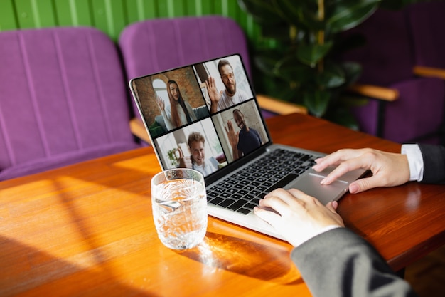 Gratis foto man met laptop voor videocall terwijl drinkwater