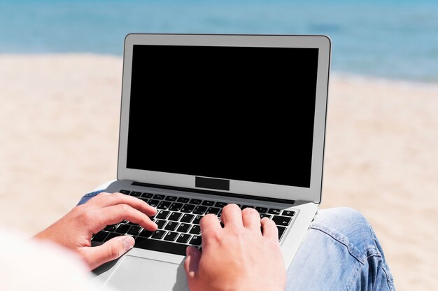Man met laptop werken op het strand
