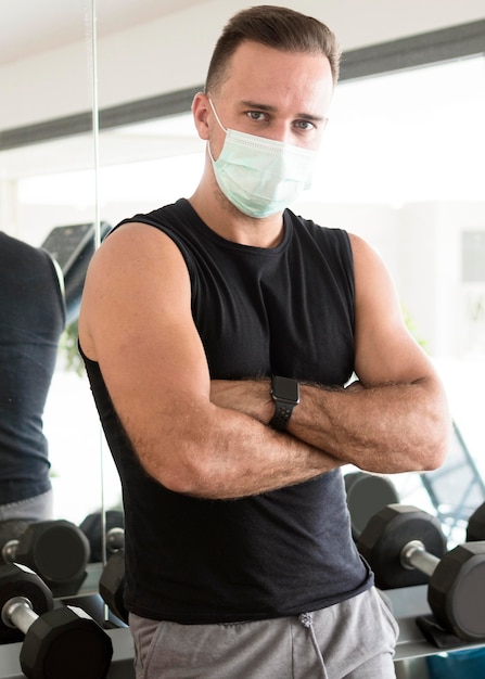 Man met medische masker poseren in de sportschool