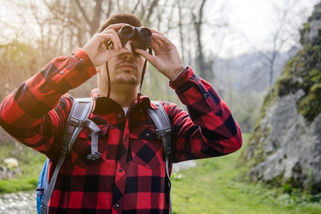 Gratis foto man met plaid shirt en verrekijker buitenshuis