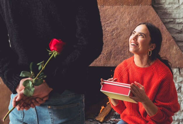 Man met roze bloem voor vrouw achter rug