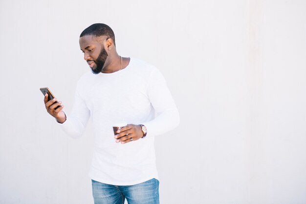 Man met smartphone en een kopje koffie