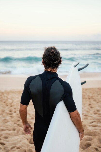 Man met surfer kleding lopen op het zand