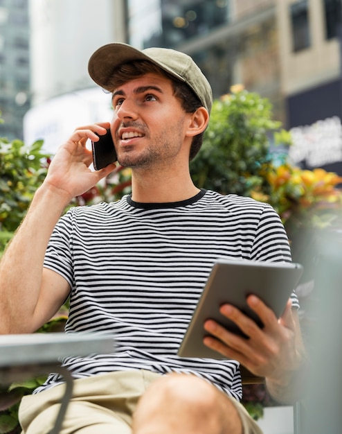 Gratis foto man met tablet in de hand praten aan de telefoon