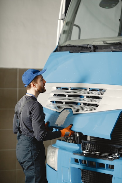 Man met tools voor vrachtwagen. Werknemer in uniform. Defecte truck