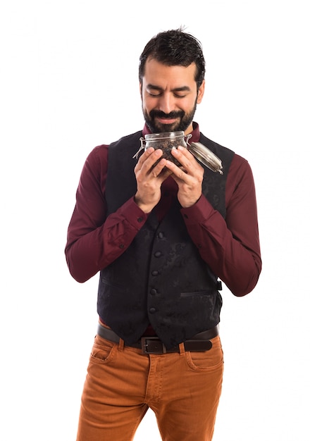 Man met vest met een potje glas met koffie binnen