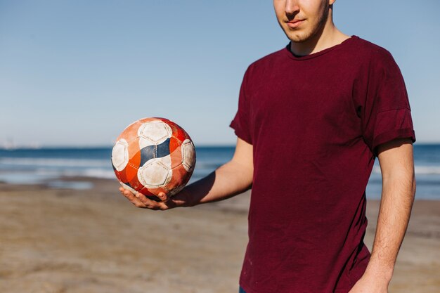 Man met voetbal in hand op het strand