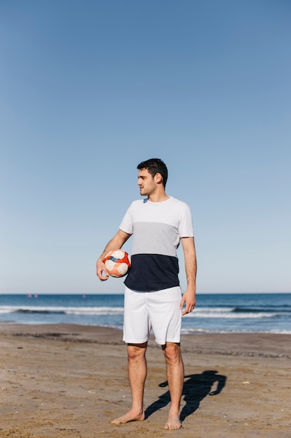 Man met voetbal op het strand