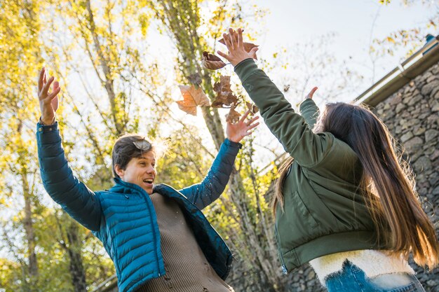 Man met zijn dochter spelen met droge herfst bladeren in park