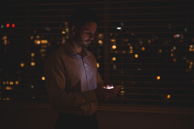 Man met zijn mobiele telefoon in de buurt van jaloezieën