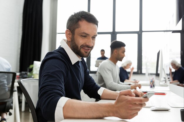 Man met zijn mobiele telefoon zittend aan zijn bureau