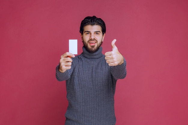 Man met zijn visitekaartje en maakt positief handteken.