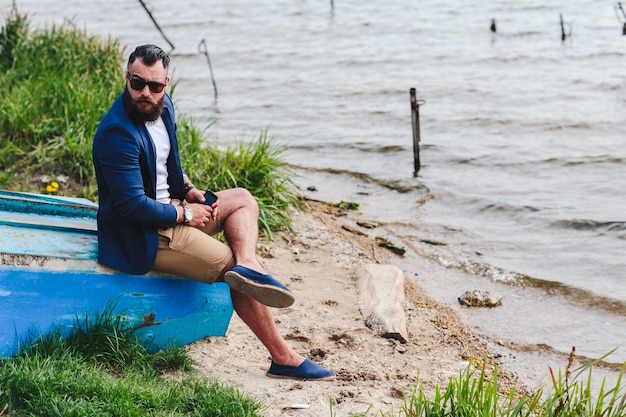 Man met zonnebril, zittend op een houten boot