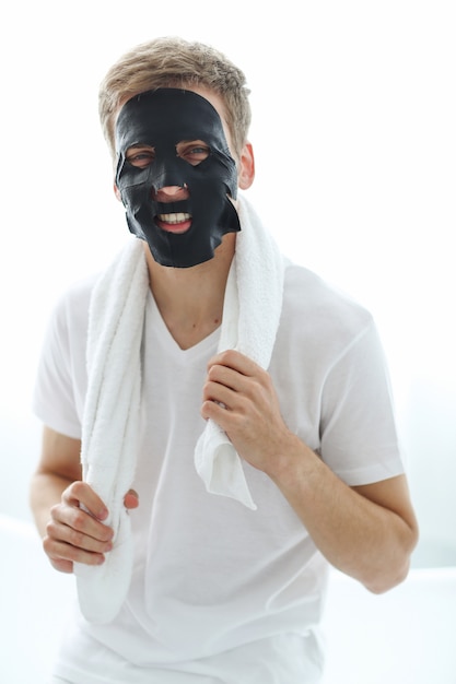 Man met zwarte gezichtsmasker, huid zuiverende houtskool. Schoonheid concept