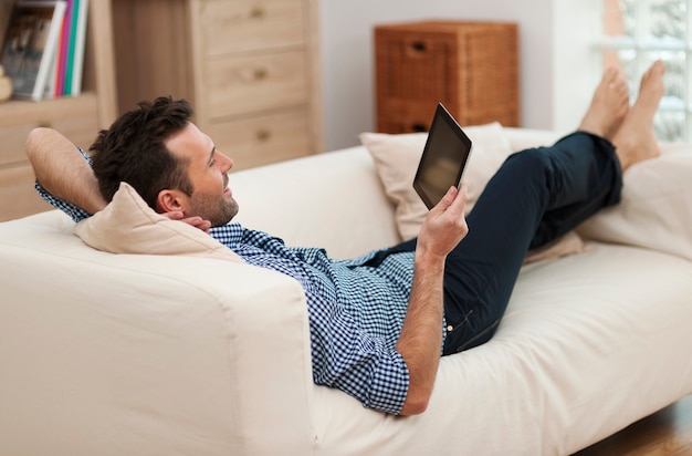 Man ontspannen met digitale tablet thuis
