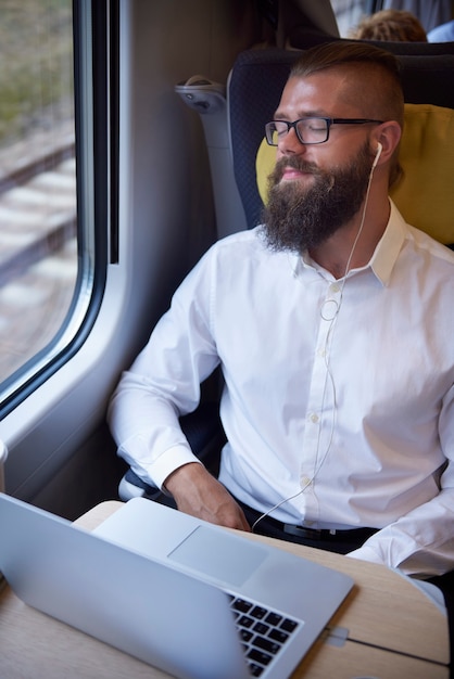 Gratis foto man ontspannen met koptelefoon in de trein