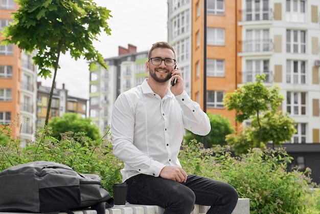 Man op bank praten via de telefoon kijken naar camera glimlachend