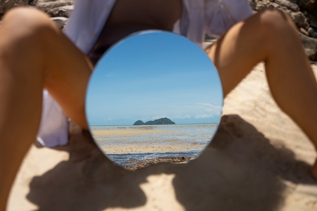 Man op het strand poseren met ronde reflecterende spiegel