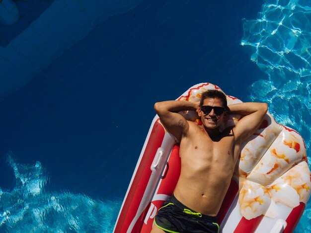 Man op strandmat in zwembad van een villahuis