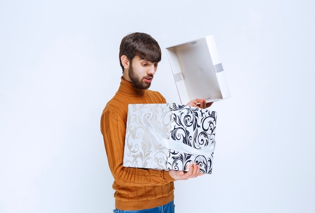 Man openen en controleren binnenkant van een witte geschenkdoos met blauwe patronen.