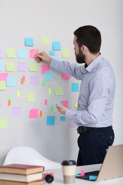 Man plakkende notities op de muur, op kantoor